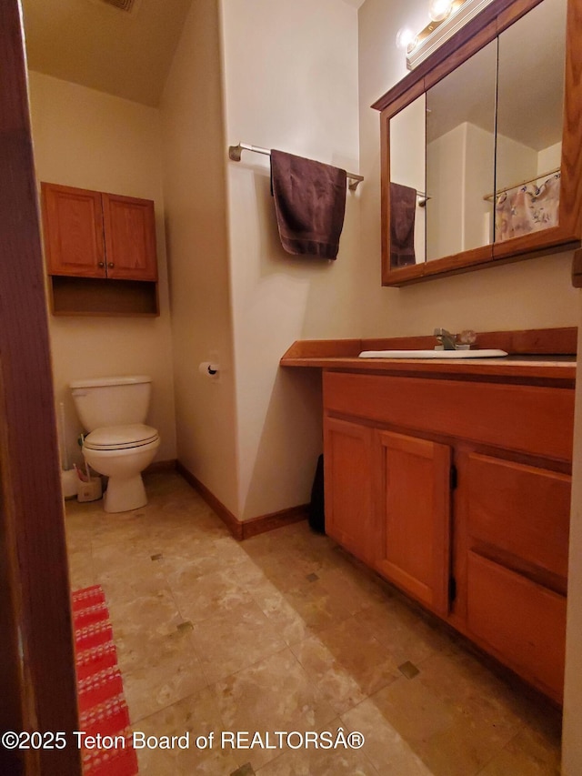 bathroom featuring toilet, baseboards, and vanity