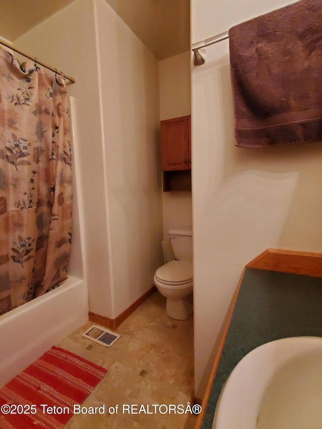 bathroom featuring toilet, shower / bath combination with curtain, visible vents, and baseboards