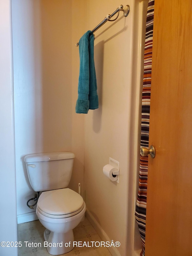 bathroom with tile patterned flooring, baseboards, and toilet