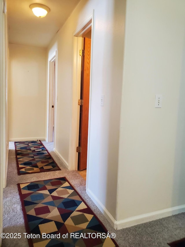 hallway featuring carpet and baseboards