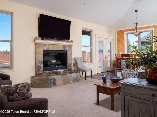 living room with wooden walls, lofted ceiling, carpet flooring, french doors, and a fireplace