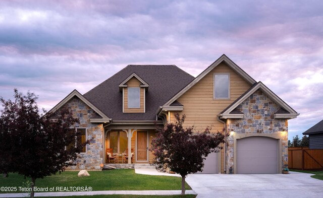 70 Baywood Dr, Driggs, ID 83422 - view of front facade featuring stone siding, concrete driveway, an attached garage, a shingled roof, and a porch