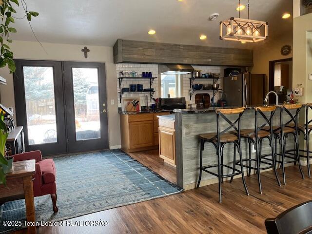 bar featuring dark wood-style floors, freestanding refrigerator, pendant lighting, and baseboards