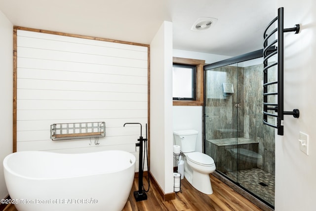 full bath featuring a freestanding tub, toilet, wood finished floors, visible vents, and a stall shower