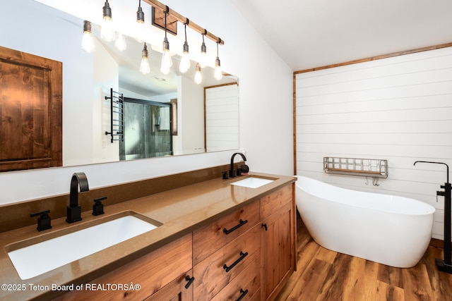 full bathroom featuring a soaking tub, a stall shower, a sink, and wood finished floors