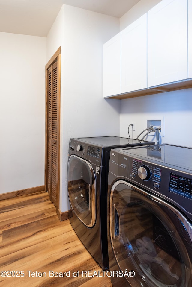 clothes washing area with washer and dryer, baseboards, cabinet space, and light wood finished floors