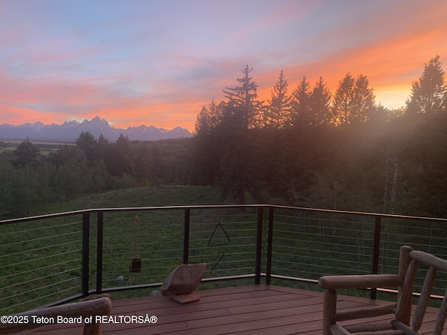 deck at dusk featuring a mountain view and a forest view