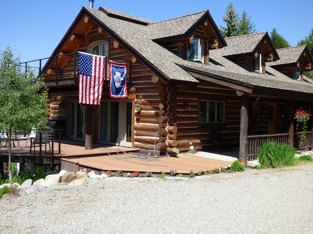 view of front of property featuring a balcony, log siding, and roof with shingles