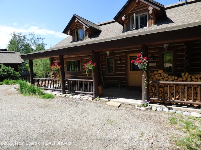 log cabin featuring log siding and a porch