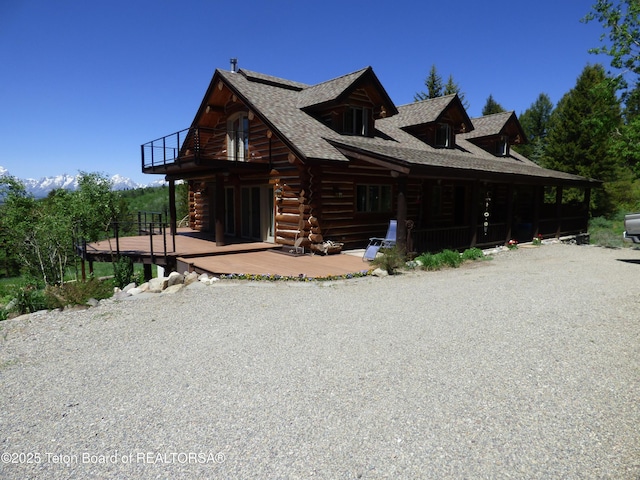 view of front of home with a balcony, log exterior, and roof with shingles