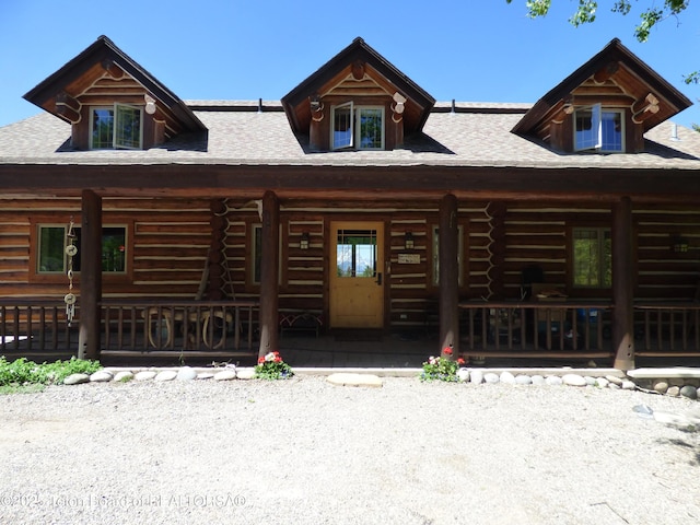 log-style house with log exterior and a porch