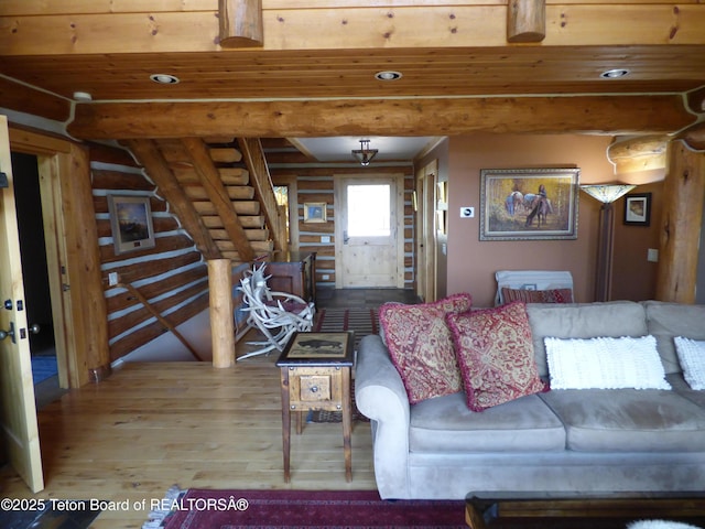 living area with stairway, beam ceiling, log walls, and wood finished floors