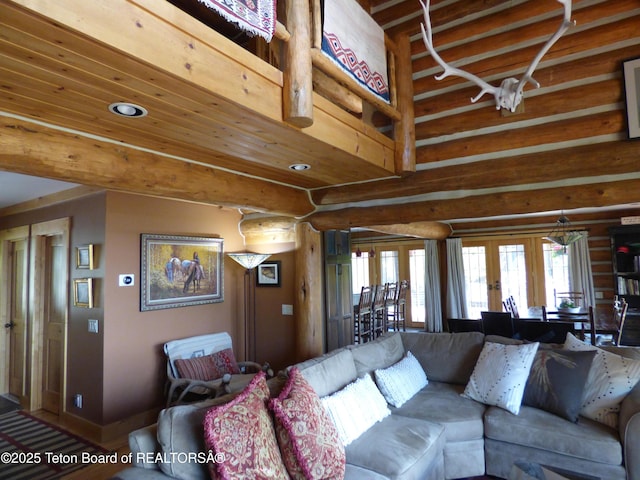 living area with french doors, beamed ceiling, rustic walls, and baseboards