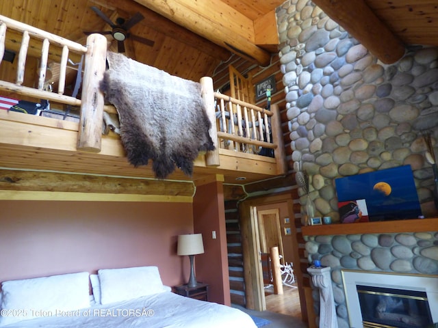 bedroom featuring beamed ceiling, a fireplace, and wood ceiling