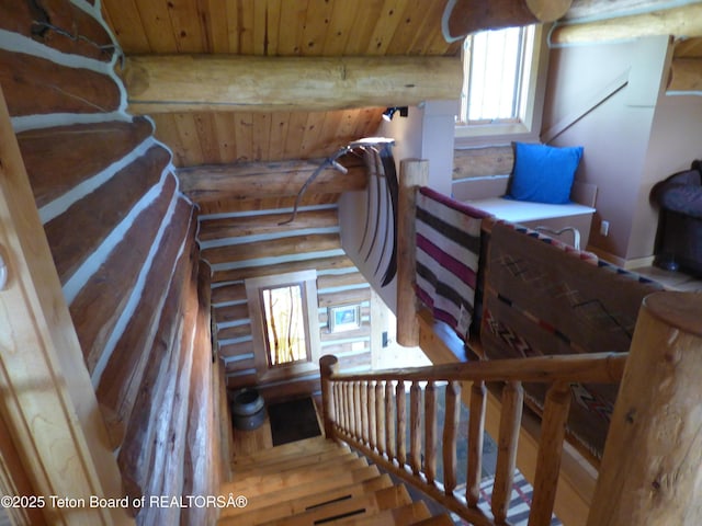 staircase with rustic walls, wood ceiling, and beam ceiling