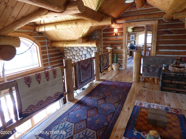 unfurnished living room with lofted ceiling with beams, wood-type flooring, a fireplace with flush hearth, and wood ceiling