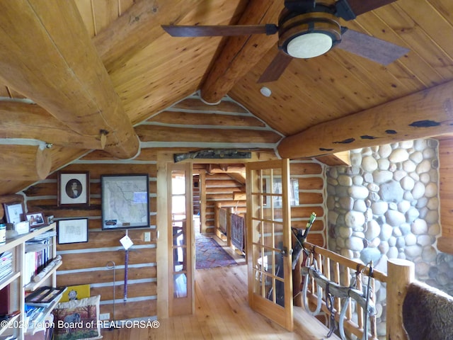 interior space with vaulted ceiling with beams, wooden ceiling, an upstairs landing, log walls, and hardwood / wood-style floors