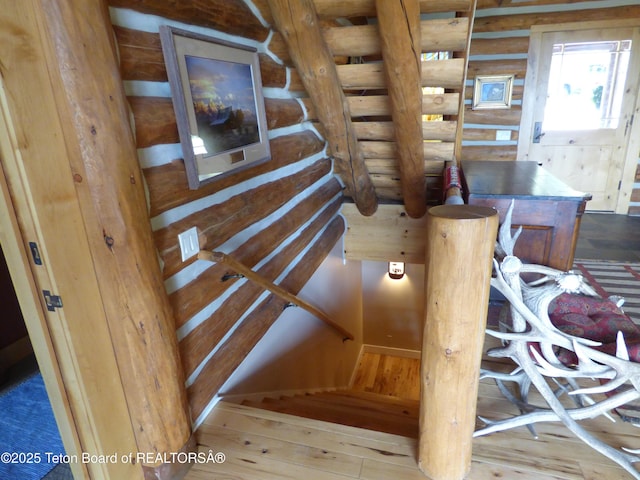 staircase featuring log walls and wood finished floors