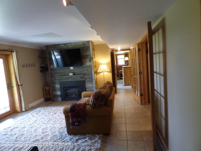 tiled living room featuring a large fireplace, visible vents, and baseboards