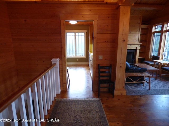 hall featuring wooden walls, an upstairs landing, and wood finished floors