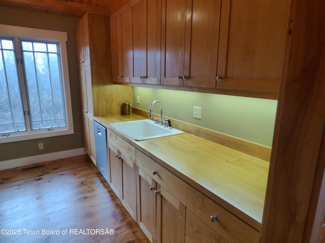 kitchen with a healthy amount of sunlight, dishwasher, light wood finished floors, and a sink