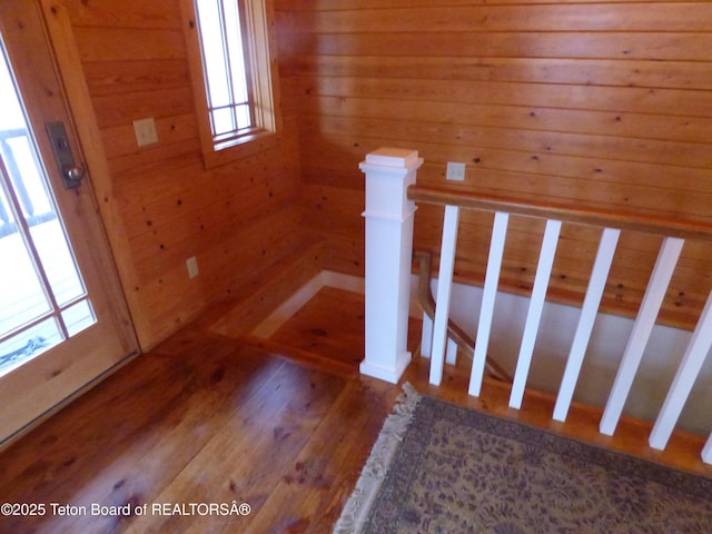 staircase with wood walls and wood finished floors