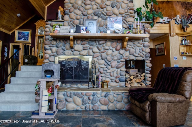 living room with lofted ceiling with beams, wood ceiling, stone finish flooring, and a stone fireplace