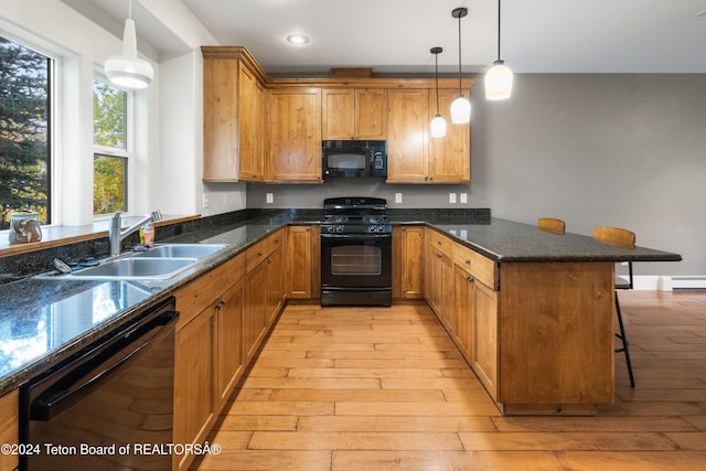 kitchen with a baseboard heating unit, a peninsula, a breakfast bar, a sink, and black appliances