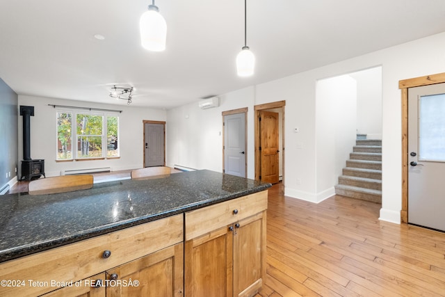 kitchen featuring a wood stove, a baseboard radiator, a wall unit AC, and decorative light fixtures