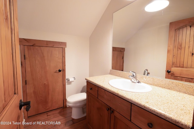 bathroom with lofted ceiling, vanity, wood finished floors, and toilet