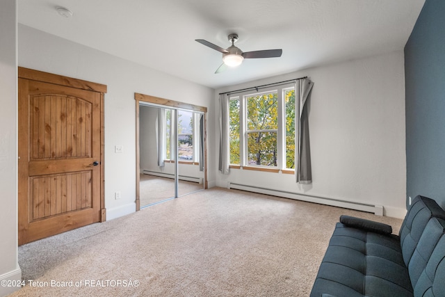 interior space featuring a baseboard heating unit, carpet floors, baseboards, and a ceiling fan