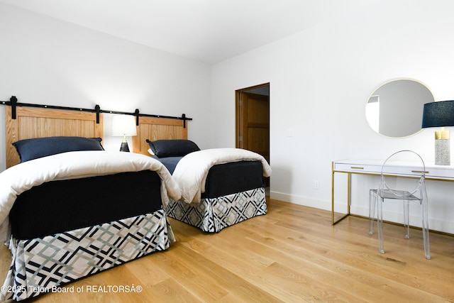 bedroom featuring a barn door, wood finished floors, and baseboards