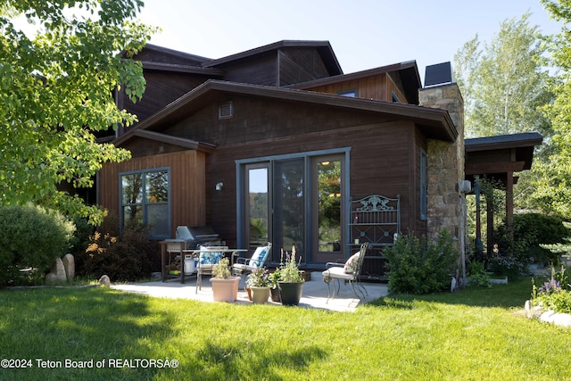 rear view of property with a patio and a lawn