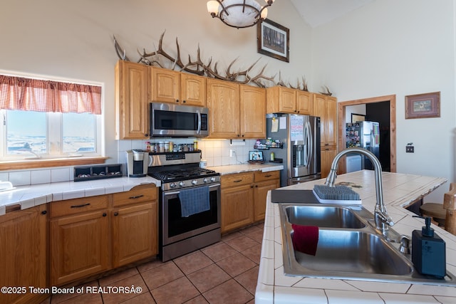 kitchen with stainless steel appliances, a sink, and tile countertops