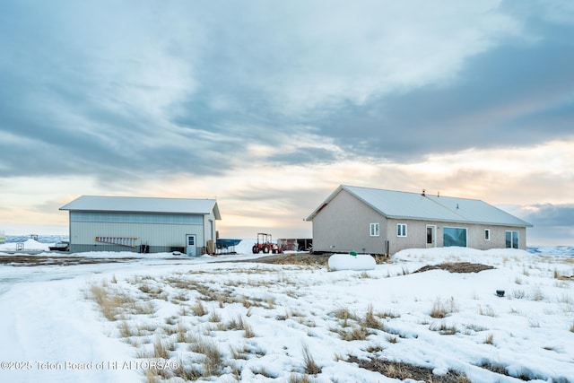 back of house at dusk featuring a pole building and an outdoor structure