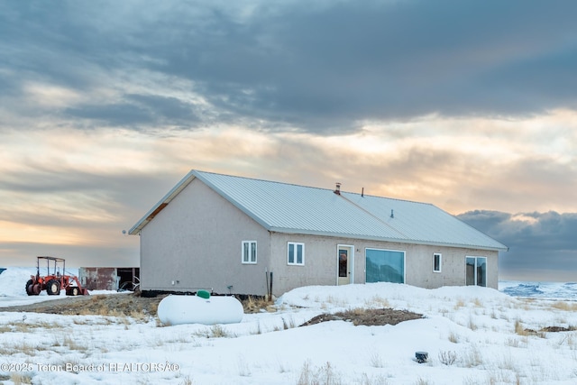 snow covered property with metal roof and stucco siding