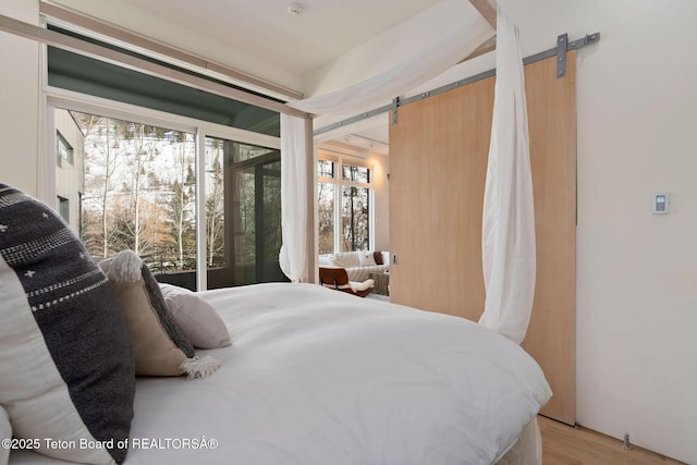 bedroom featuring light wood-style floors and a barn door