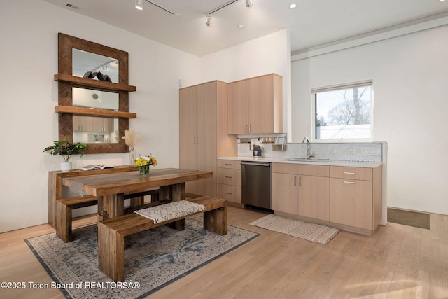 kitchen featuring light wood-type flooring, a sink, light countertops, and dishwasher