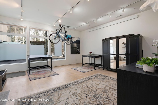 interior space with rail lighting, visible vents, and wood finished floors