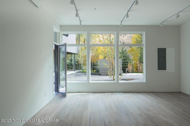 empty room with rail lighting, electric panel, and a healthy amount of sunlight