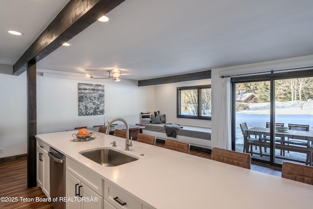 kitchen featuring dark wood-type flooring, a sink, white cabinets, light countertops, and beam ceiling