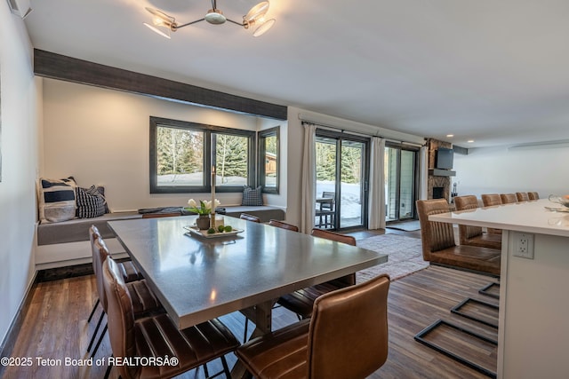 dining space with dark wood-type flooring and a stone fireplace