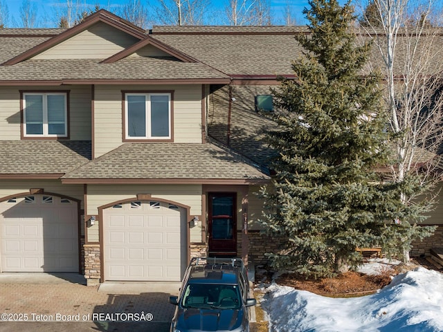 multi unit property featuring an attached garage, driveway, and a shingled roof