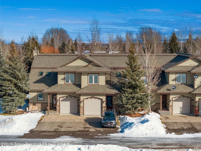 view of front of house featuring an attached garage, stone siding, driveway, and roof with shingles