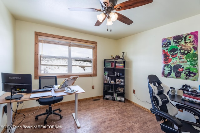 office with baseboards, visible vents, a ceiling fan, and wood finished floors