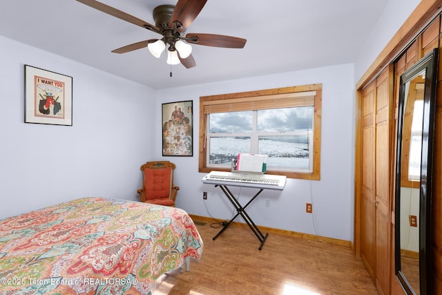 bedroom with light wood-style floors, a closet, ceiling fan, and baseboards