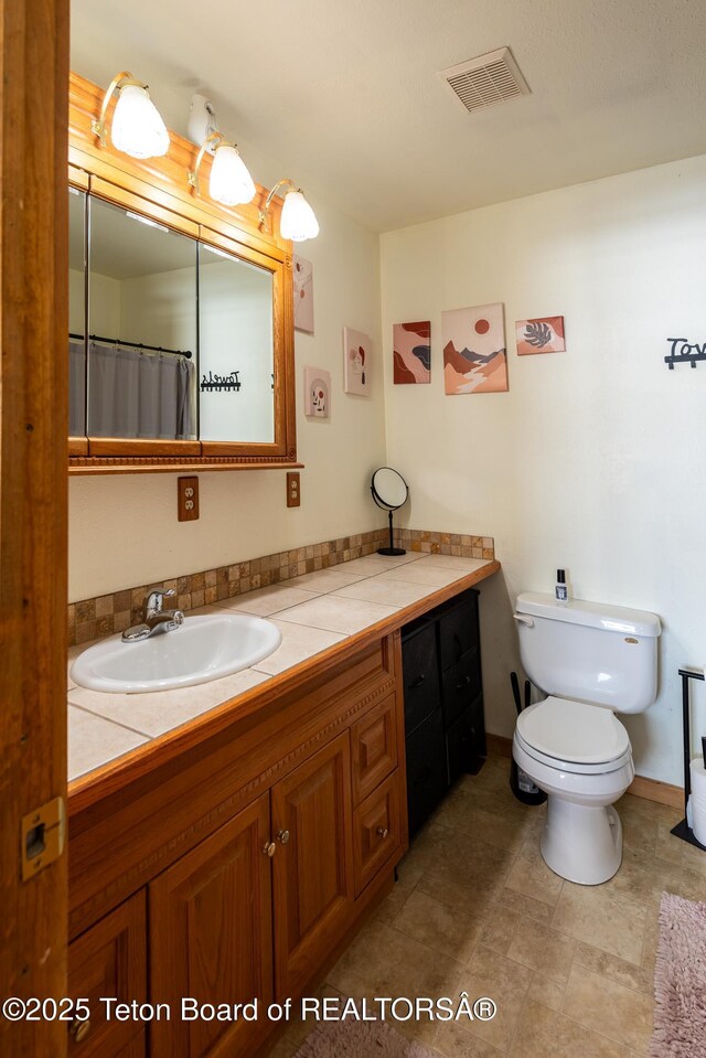 full bathroom with toilet, visible vents, and vanity