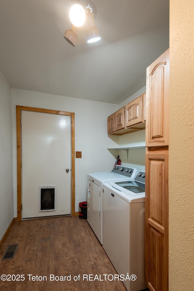 laundry room featuring washer and dryer, dark wood-style flooring, cabinet space, and visible vents