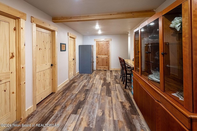 hall featuring dark wood finished floors, beamed ceiling, and baseboards