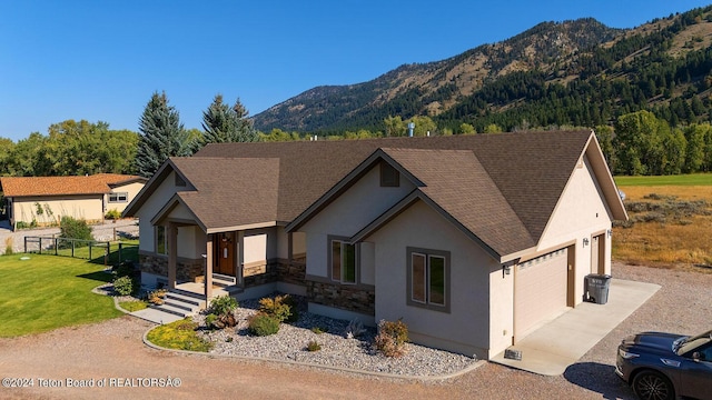 modern farmhouse style home featuring stucco siding, stone siding, fence, a mountain view, and a garage